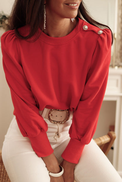 Blusa de manga larga con detalle de botón rojo