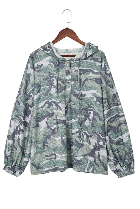 Slip into this oversized, camo-print hoodie! Drop shoulder, wide sleeves, and buttoned neck - not to mention the waffle-knit texture - make it unequivocally fashionable. 95% Polyester, 5% Elastane, so you know it's comfy and available in Green from Moodz Boutique. One hoodie - infinite styling possibilities!